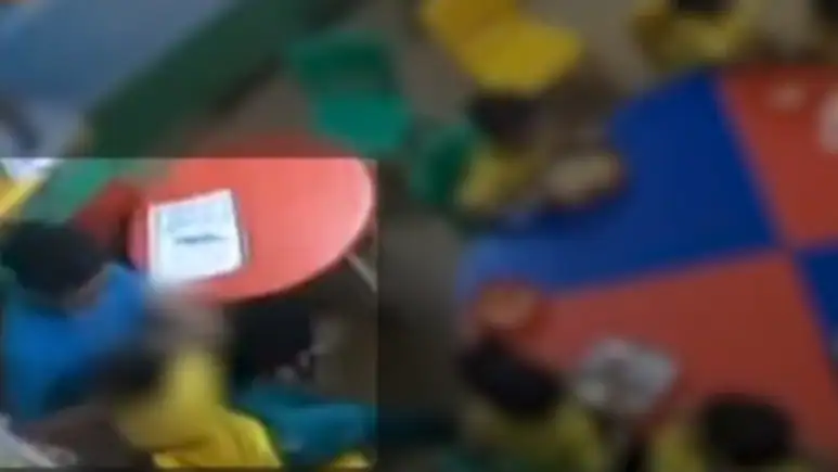 She pushes the three-year-old who is in a small yellow plastic chair across the tiled floor