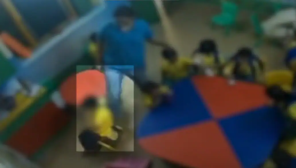 She pushes the three-year-old who is in a small yellow plastic chair across the tiled floor